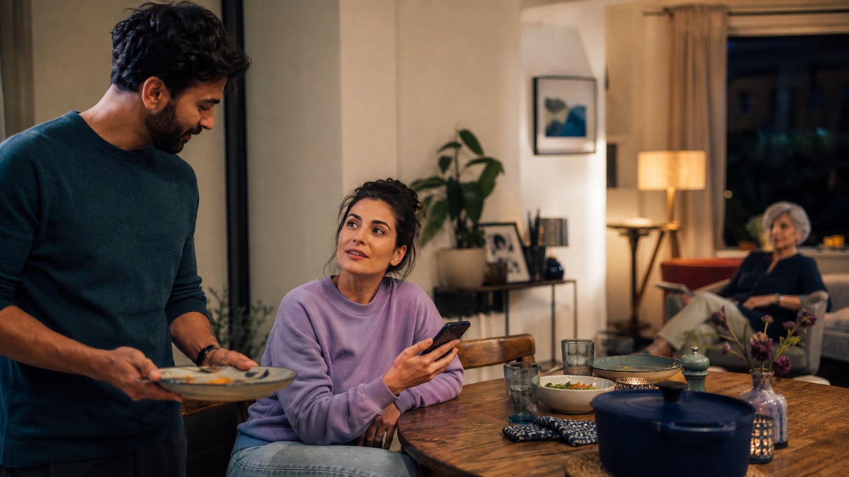 Household members talking together after dinner while briefly checking a phone